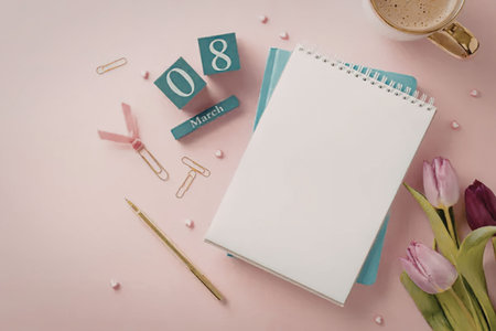 A serene and organized workspace with a notebook, tulips, and stationery on a pink background