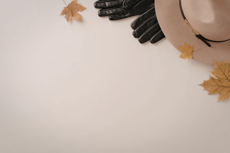 A stylish arrangement of autumnal accessories including a hat, gloves, and fallen leaves.