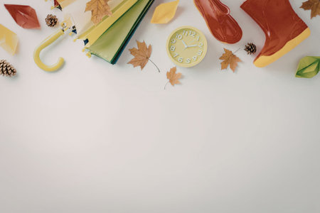 A colorful arrangement of autumnal items including umbrellas, rain boots, leaves, and pinecones.