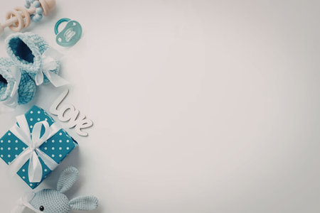 A blue gift box with white polka dots and a white ribbon tied around it, surrounded by blue flowers and other decorative items on a white background.