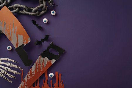 A spooky halloween setup with bloody knives, chains, bats, eyes, and skeleton hand on purple...