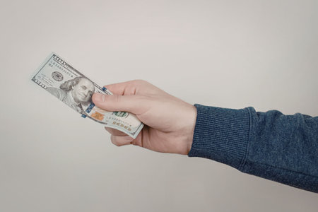 A hand holding banknotes against a plain background