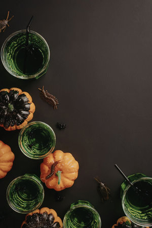 An overhead shot of small pumpkins and green drinks on a black background, perfect for Halloween celebrations.の写真素材