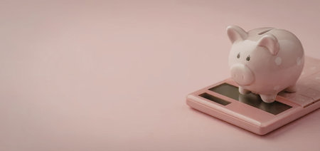 A pink piggy bank sitting on top of a pink calculator with a pink background