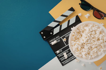 A colorful arrangement of movie night essentials including popcorn, a clapperboard, and 3D glasses...