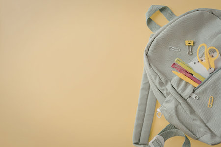 A light blue school backpack with colorful stationery and school supplies peeking out of its pocket,...