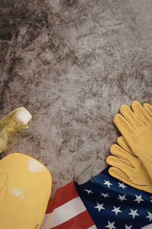 A yellow hard hat, a bottle, and a pair of yellow gloves on an American flag