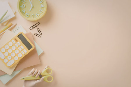 A collection of school supplies on a desk including a calculator, scissors, clock, and paper.