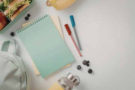 A neatly arranged selection of back to school items on a clean white surface, including a backpack,...