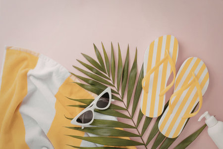 A collection of summer vacation essentials including flip flops, sunglasses, and a towel, arranged...