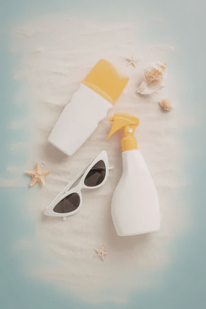 Sunscreen bottles and sunglasses on a sandy beach with starfish and seashells