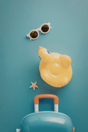 A collection of summer vacation items including a suitcase, inflatable duck, sunglasses, and...