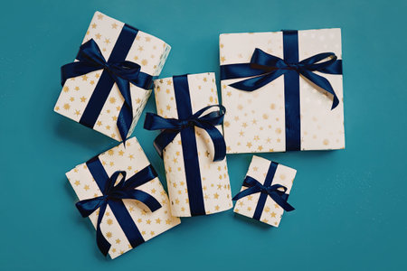 A collection of elegantly wrapped gifts with blue ribbons on a turquoise background