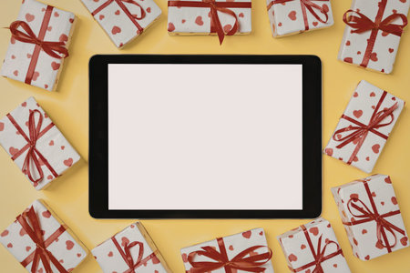 A tablet surrounded by wrapped gift boxes on a yellow background