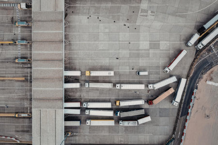An aerial view of a logistics hub with multiple trucks parked in an organized manner, showcasing a busy transportation hub.