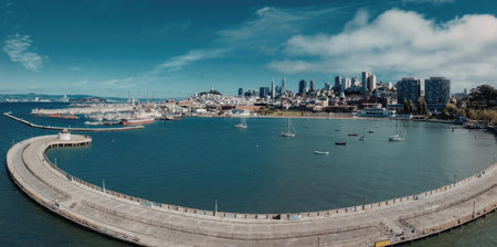 A panoramic view of San Francisco Bay with a curved concrete seawall in the foreground and the city skyline in the background