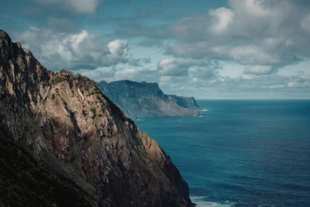 A scenic view of a large body of water with cliffs in the foreground and background under a cloudy sky.