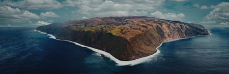 The image captures a breathtaking aerial view of a small island with lush greenery, surrounded by deep blue ocean waters and white waves crashing against its shores.