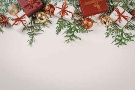 A festive arrangement of Christmas gifts, pine branches, and ornaments on a white background.