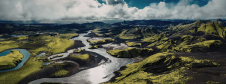 A serene river winds its way through a vibrant green landscape, surrounded by rolling hills and a dramatic cloudy sky.
