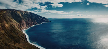 A serene and breathtaking ocean view with lush green mountains on one side and clear blue sky above, showcasing the beauty of nature.