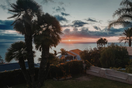 Serene sunset over tropical landscape with house and palm trees