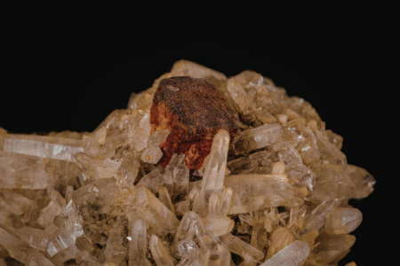 This image shows a cluster of quartz crystals with a red inclusion. The quartz crystals are transparent and brownish in color, while the inclusion is a deep red. The background of the image is black, which helps to highlight the details of the crystals.