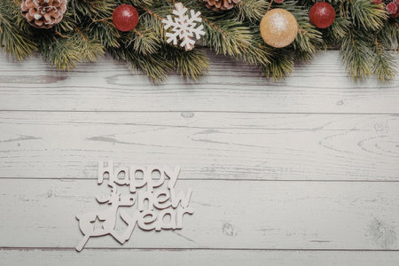 A festive Christmas decoration with a 'Happy New Year' message on a white wooden background, adorned with pine branches, red and gold ornaments, and snowflakes.