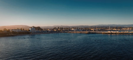 A serene waterfront cityscape at sunset, with a large body of water in the foreground and a city skyline in the background.