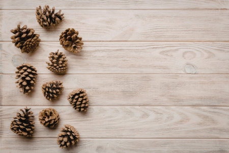 A group of pine cones placed on a light-colored wooden background, possibly for decorative or seasonal purposes.