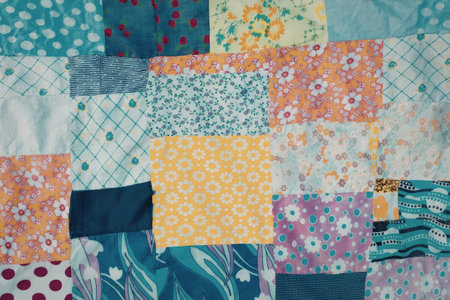 A close-up of a colorful patchwork quilt featuring various floral patterns and geometric designs in shades of blue, orange, pink, and yellow.