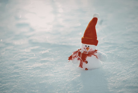 a small snowman wearing a red hat and scarf in the snow