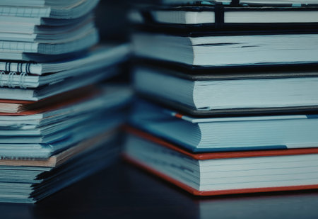 A stack of books piled on top of each other, with some books having red or black covers.