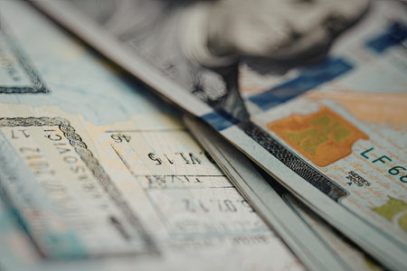 A close-up view of a stack of US dollar bills, showcasing their colorful designs and security features.