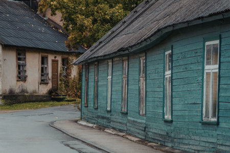 a green wooden building with a grey roof is next to a tan building with a black roof