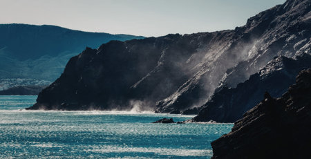 a large body of water with a mountain range in the background. the water is bright blue and calm, reflecting the sunlight. the mountains are dark and rugged, with some snow visible on the peaks.