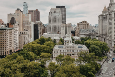 a cityscape with a large white building surrounded by green trees, with many tall buildings in the background, some of which are colored in green and yellow
