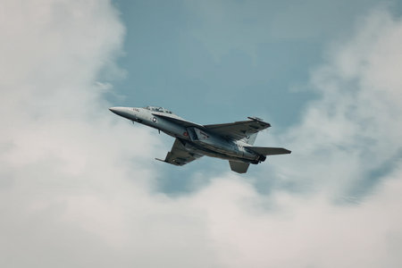 a gray fighter jet with a pointed nose and two wings is flying through a blue sky with white clouds