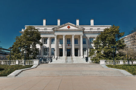 a large white building with columns and a red star on the front, surrounded by trees and a clear blue sky