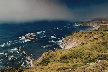 a rocky coastline with green grass and a blue ocean under a cloudy sky
