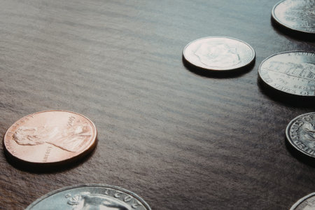 A collection of coins on a dark wooden surface, including a penny and several other coins.