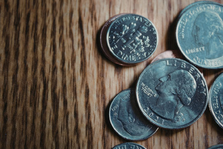 A pile of coins on a wooden table or floor, showcasing their details and texture.