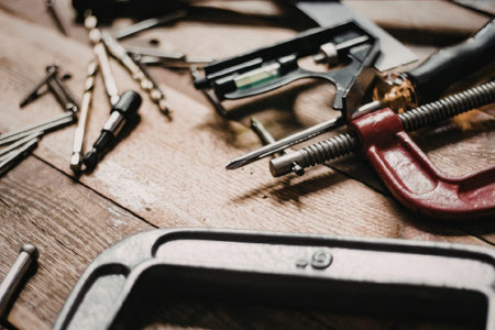 A close-up of a workbench with various tools and screws, including a red clamp.
