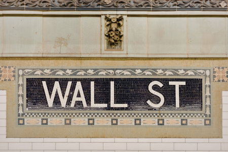 a close-up shot of a street sign that reads wall st on a green building