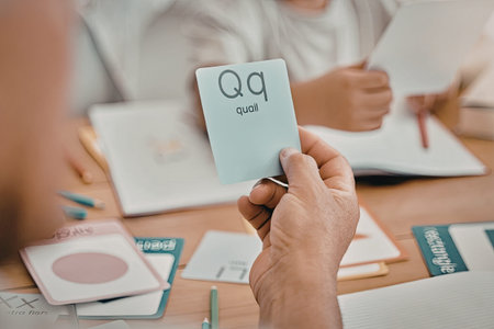 a person is holding up a flashcard with a quail on it while sitting at a table with other people and educational materials