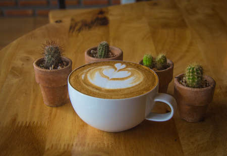 A cup of coffee with heart pattern in a white cup on wooden backgroundの写真素材