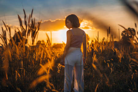Silhouette of a young woman relaxing on a beautiful sunset. Woman enjoying nature sunset.の写真素材