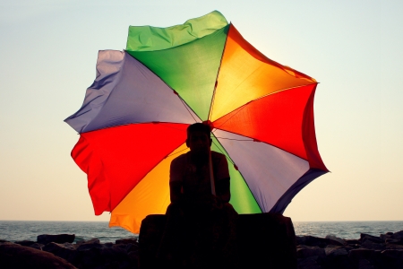 A silhouette of a man with a big rainbow umbrellaの写真素材