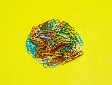 Colorful paper clip isolated on yellow backgroundの写真素材
