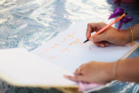 Hand of guests holding pens writing on a Wedding Signing booksの写真素材